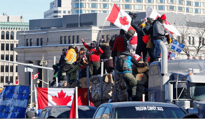 Protestors stand on a trailer carrying logs in Ottawa